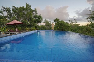 Una piscina al aire libre, sombrillas, sillones reclinables de piscina
