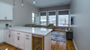 Een moderne keuken met witte kasten, een groot eiland en stadszicht door grote ramen.