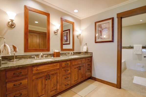 Un baño con armarios de madera, dos lavamanos y un espejo grande.