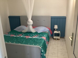 Un dormitorio con una cama, una mesita de noche, una silla y una ventana.