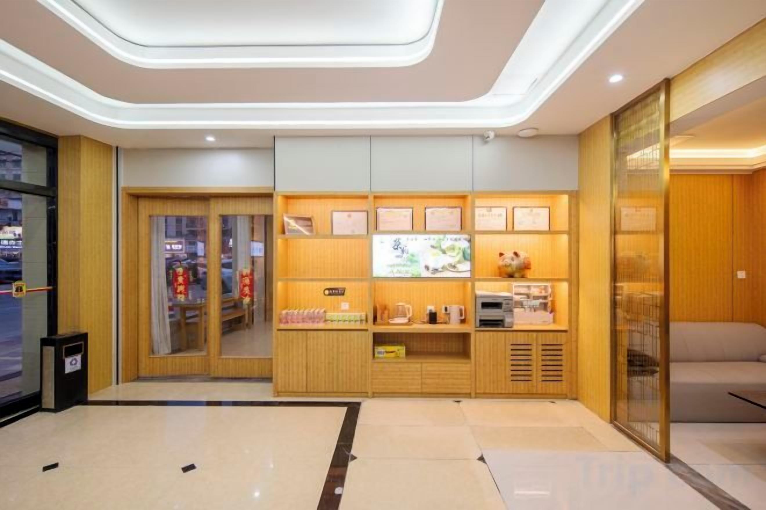 A hotel lobby with a reception desk, seating area, and a wall with framed certificates.