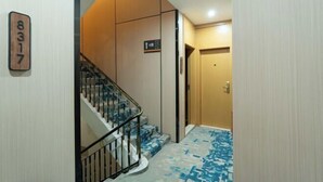 A hotel interior with a staircase, a wooden door, and a sign indicating the 4th floor. - Super 8 Hotel (Quanzhou Nan'an Hongse Laifulong Shopping Plaza) (Nan'an)