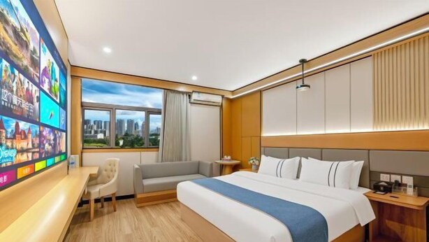 A modern hotel room with a large bed, a seating area with a sofa and chair, a TV mounted on the wall, and a window with a city view. - Super 8 Hotel (Quanzhou Nan'an Hongse Laifulong Shopping Plaza) (Nan'an)