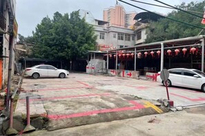 A parking area with a white car and a building with red lanterns. - Super 8 Hotel (Quanzhou Nan'an Hongse Laifulong Shopping Plaza) (Nan'an)