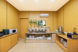 A compact kitchen with wooden paneling, a microwave, a coffee machine, and a shelf with dishes. - Super 8 Hotel (Quanzhou Nan'an Hongse Laifulong Shopping Plaza) (Nan'an)
