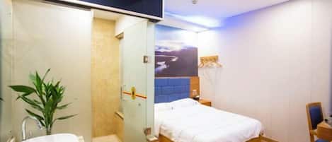 A modern hotel room with a large bed, a bathroom with a sink and shower, and a view of the cityscape.