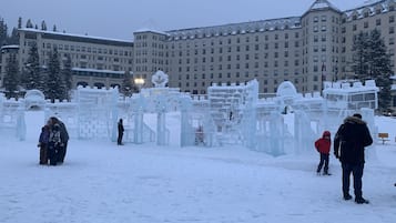 A snow-covered outdoor area with ice sculptures and a large building in the background.