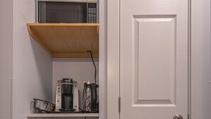 Une cuisine compacte équipée d’un four à micro-ondes, d’une machine à café et d’un petit réfrigérateur.