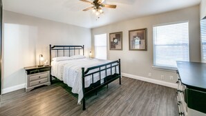 Ein Schlafzimmer mit einem Bett, Nachttischen, einem Deckenventilator und gerahmten Bildern an der Wand.