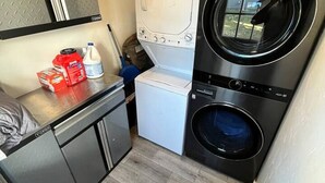A compact laundry room with a washing machine, dryer, and a small sink area.