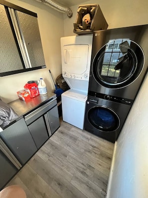 A compact laundry room with a washing machine, dryer, and a small sink area.