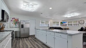 Una cocina amplia con armarios blancos, un refrigerador de acero inoxidable y una encimera de granito.