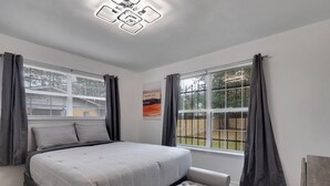 Un dormitorio con una cama grande, un banco y una lámpara en el techo.