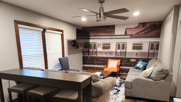 A compact living space with a dining area, a sofa, and a kitchen area with a subway mural. - The Railroad Ranch - Station Five (Youngstown)