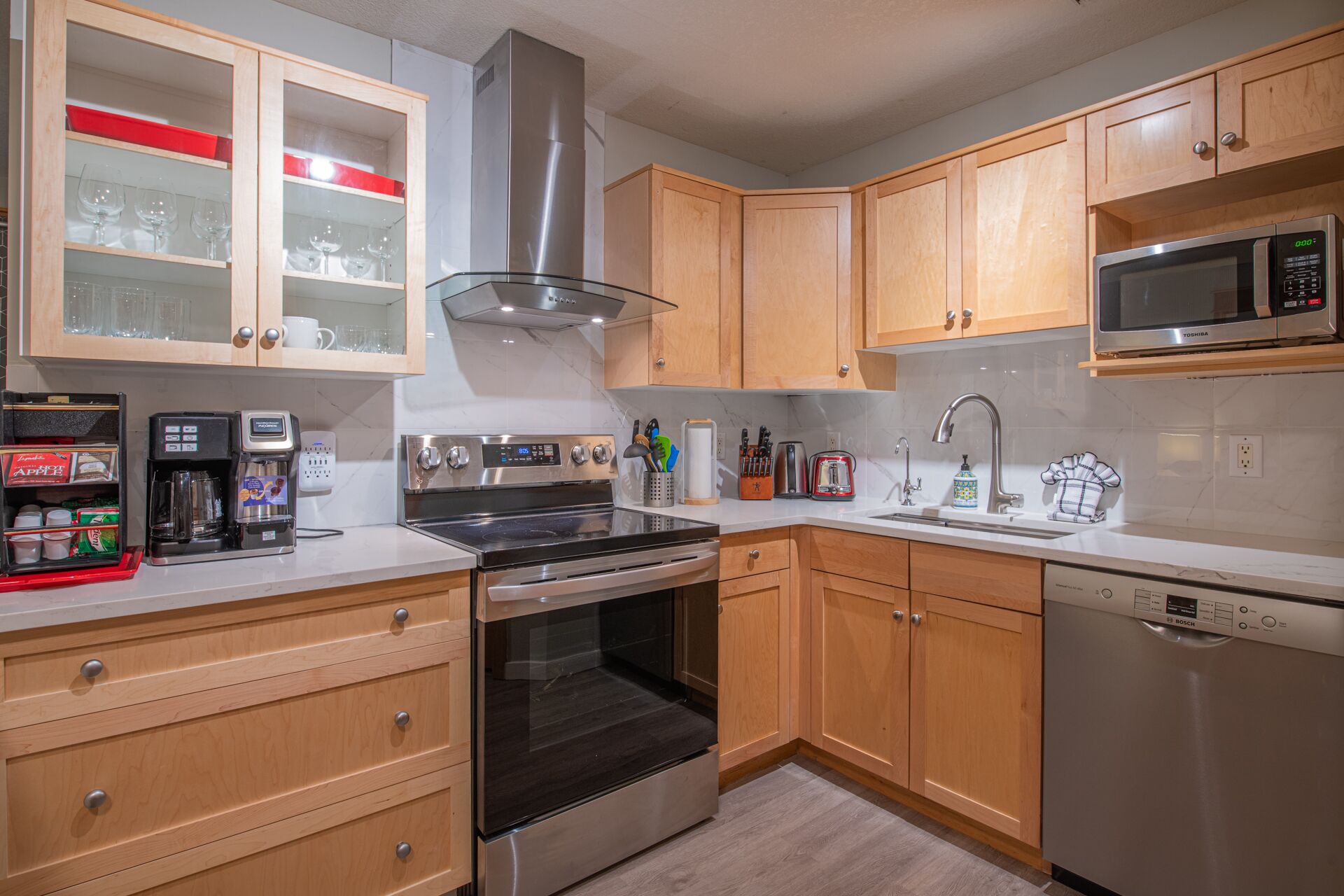 A modern kitchen with wooden cabinets, a stainless steel stove, a microwave, and a Bosch dishwasher.