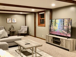 A living room with a sofa, armchairs, a coffee table, and a TV on a wooden stand. - Truyen Quach (Lincoln)