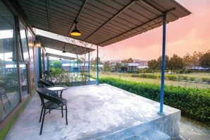 A covered outdoor seating area with a table and chairs, overlooking a landscaped garden and distant buildings. - Daxiagu Ligong Guoyuan Holiday Hotel (Ruyuan)