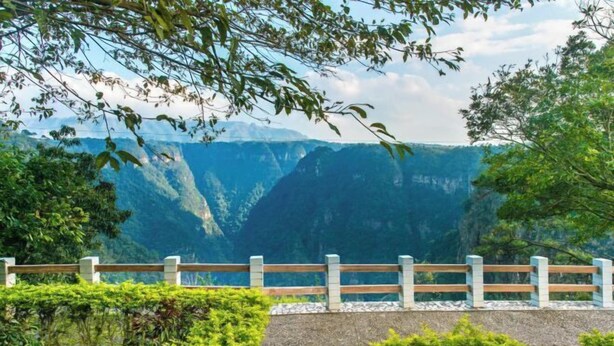 A scenic overlook with a wooden fence and lush greenery. - Daxiagu Ligong Guoyuan Holiday Hotel (Ruyuan)