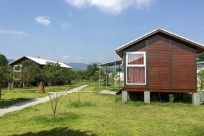 A modern wooden cabin with a glass door, surrounded by a grassy area and a clear sky. - Daxiagu Ligong Guoyuan Holiday Hotel (Ruyuan)