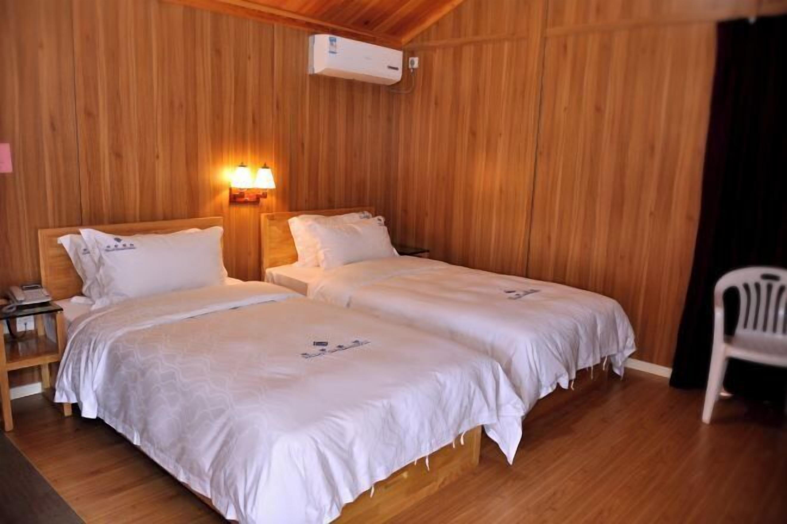 Une chambre avec deux lits, des murs en bois, une table de chevet avec un téléphone et un appareil de climatisation.