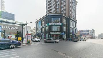 A street view with a Huawei store, a multi-story building with signage, and several cars.