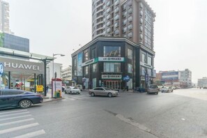 A street view with a Huawei store, a multi-story building with signage, and several cars. - Sibaike Hotel (Zhongshan)