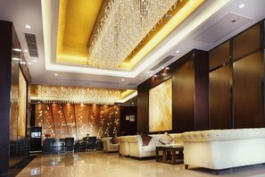 A hotel lobby with a reception desk, seating area, and a large chandelier. - Sibaike Hotel (Zhongshan)