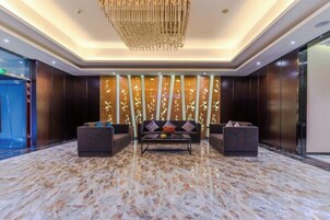 A lobby with a marble floor, a chandelier, a sofa, and a reception desk.