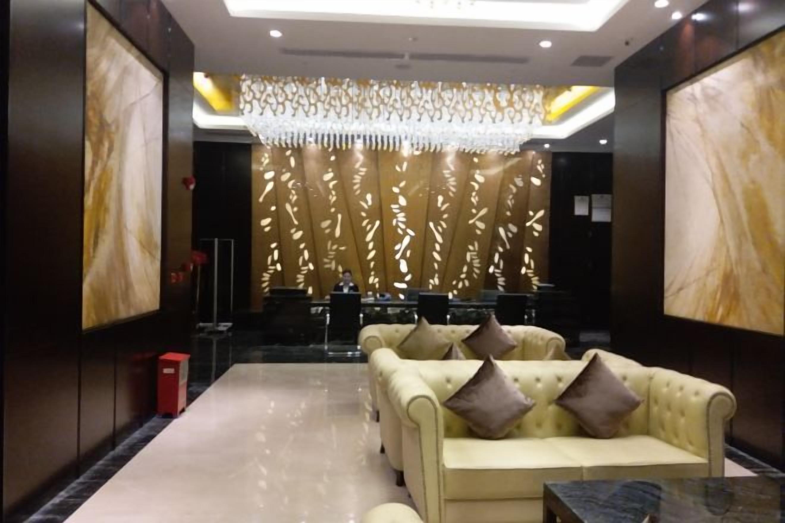 A lobby with a reception desk, seating area, and a decorative wall.