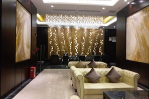 A lobby with a reception desk, seating area, and a decorative wall. - Sibaike Hotel (Zhongshan)