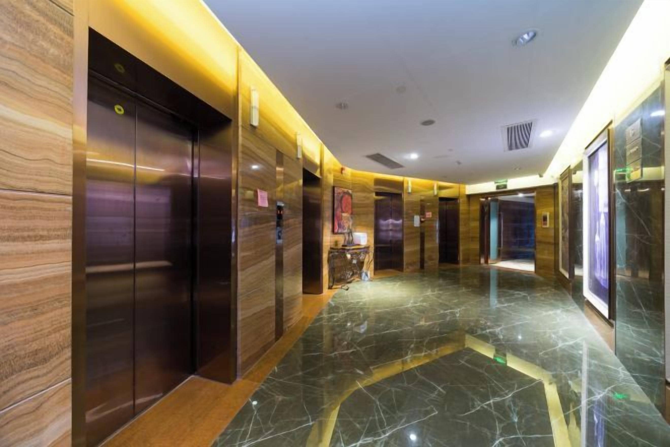 Een moderne hotellobby met marmeren vloeren, liften en een receptie.