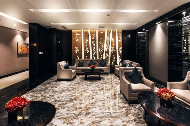 A modern lounge area with a marble floor, sofas, a coffee table, and decorative vases.