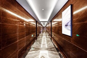 Un pasillo largo y estrecho con piso y paredes reflectantes, que conduce a una puerta al final.