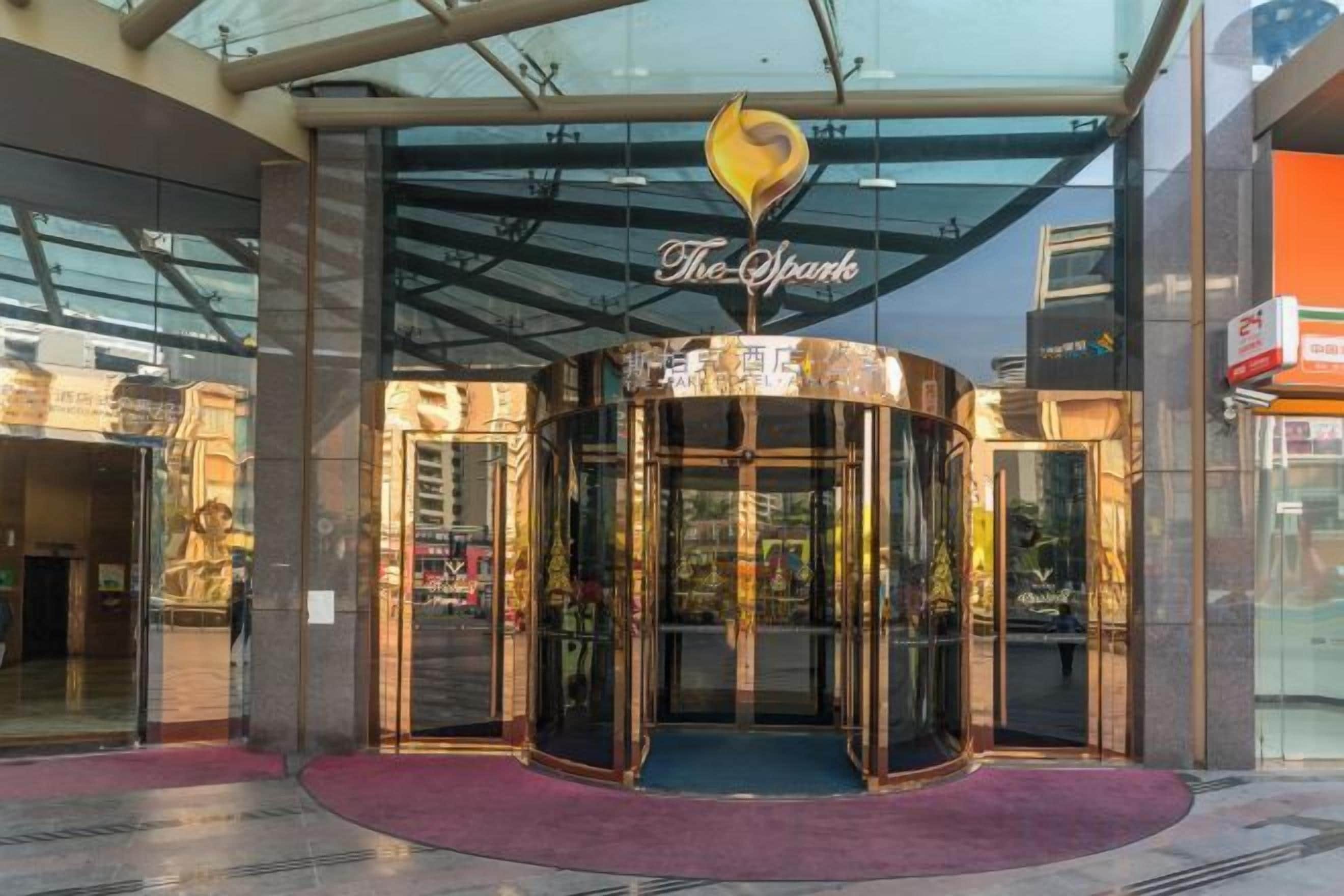 A revolving door entrance to a building with a glass canopy and a sign above it.