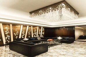 A modern lobby with a sectional sofa, a coffee table, and a decorative wall with vertical elements. - Sibaike Hotel (Zhongshan)