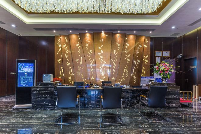 A reception area with a marble floor, a reception desk, and a decorative wall with leaf patterns.