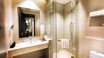 A modern bathroom with a glass shower enclosure, a sink with a mirror, and a toilet.