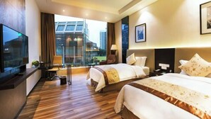A hotel room with a large bed, a TV, a desk, and a view of the city. - Sibaike Hotel (Zhongshan)