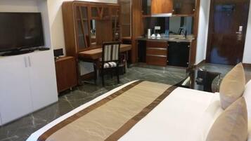 Ein Hotelzimmer mit Bett, Fernseher, Schreibtisch mit Stuhl, Spiegel und Kleiderschrank.