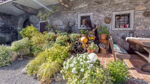 A rustic stone building with a balcony, a gravel courtyard, and various potted plants. - Countryside House Gal (Sezana)