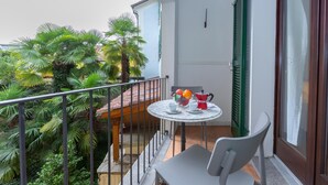 Ein Balkon mit Tisch für zwei Personen, einem Stuhl und Blick auf üppiges Grün.
