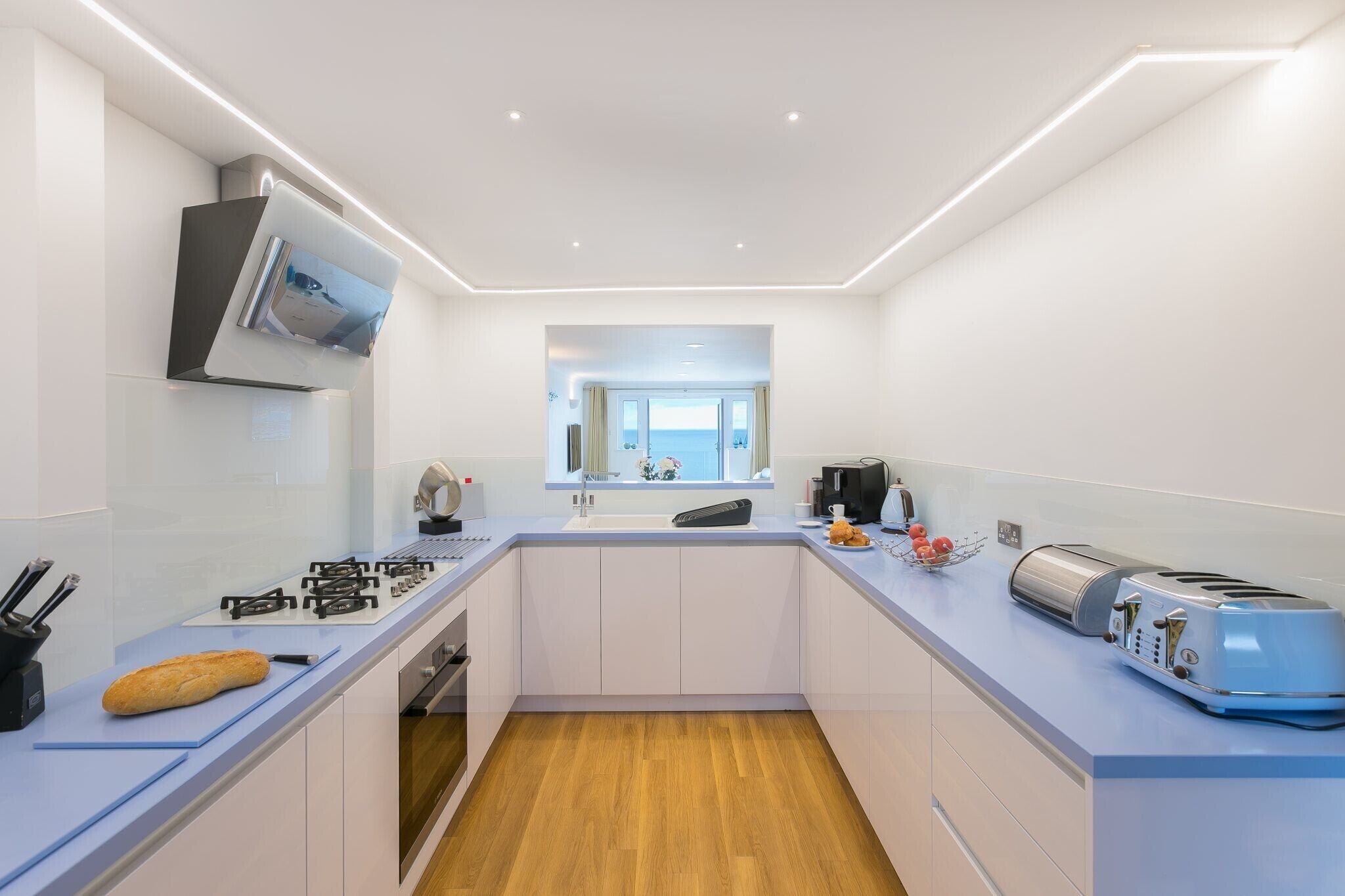 Une cuisine moderne avec des meubles blancs, un four encastré, une cuisinière et un grille-pain.