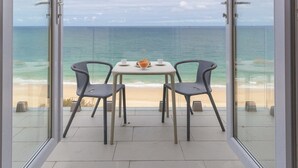 Un balcon avec une table et des chaises donnant sur une plage.