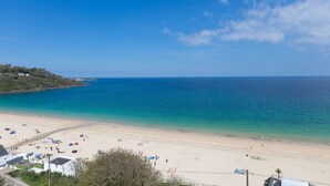 Une plage avec une eau d’un bleu limpide, un rivage sablonneux et quelques parasols.