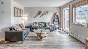 A modern living room with a leather sofa, a round coffee table, and a bookshelf. - Spacious Condo, Great Location & Mountain Views (Canmore)
