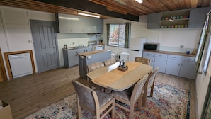 Une cuisine moderne avec des meubles de couleur grise, une table à manger en bois et un tapis à motifs.