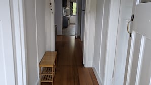 Un couloir doté d’un plancher en bois, de murs blancs et d’une petite table.