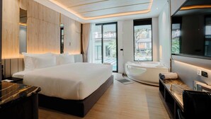 A modern hotel room with a large bed, a seating area with a massage chair, a flat-screen TV, and a large window offering a view of the outside. - RICHMANN RESORT HOTEL HATYAI (Hat Yai)