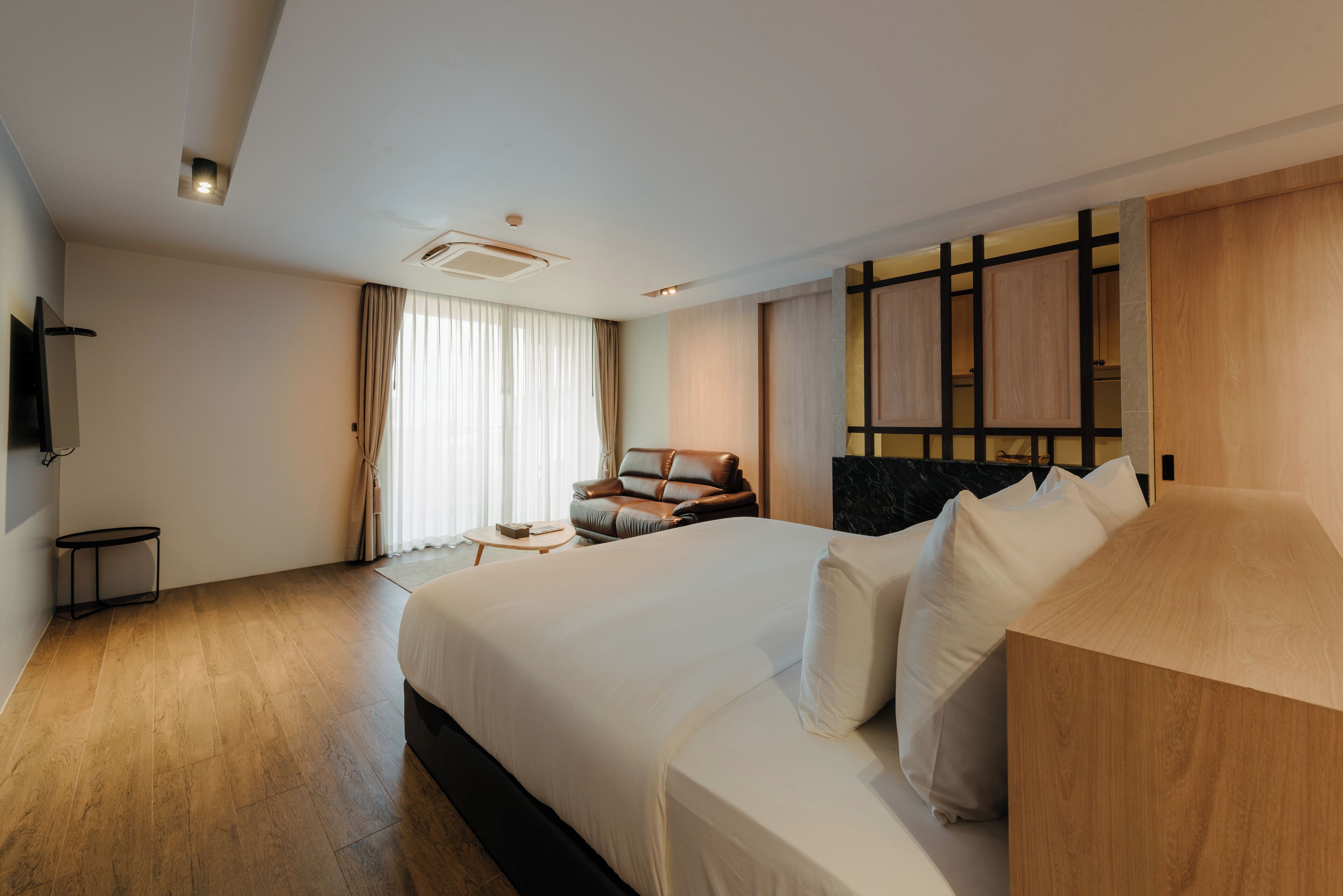 Ein modernes Hotelzimmer mit einem großen Bett, einer kleinen Sitzecke und einem Fernseher.