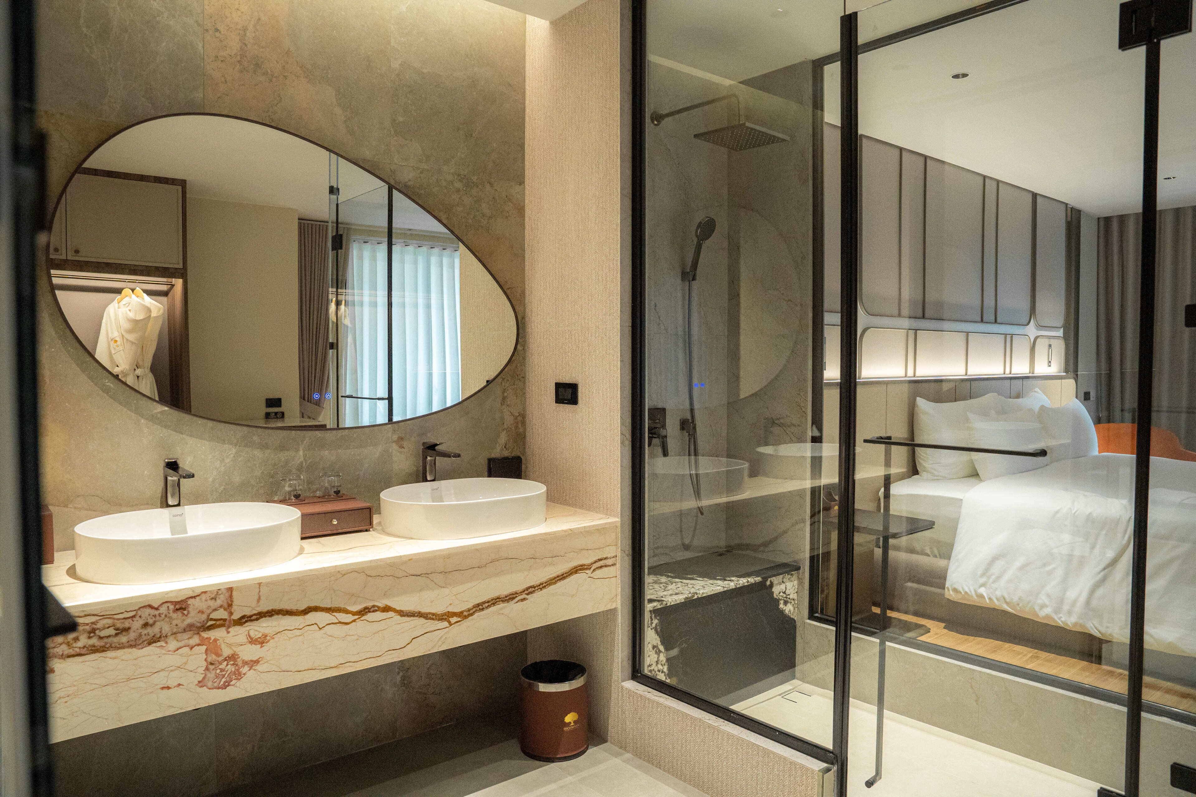 Un baño moderno con un espejo grande, dos lavamanos y cabina de ducha con paredes de vidrio.
